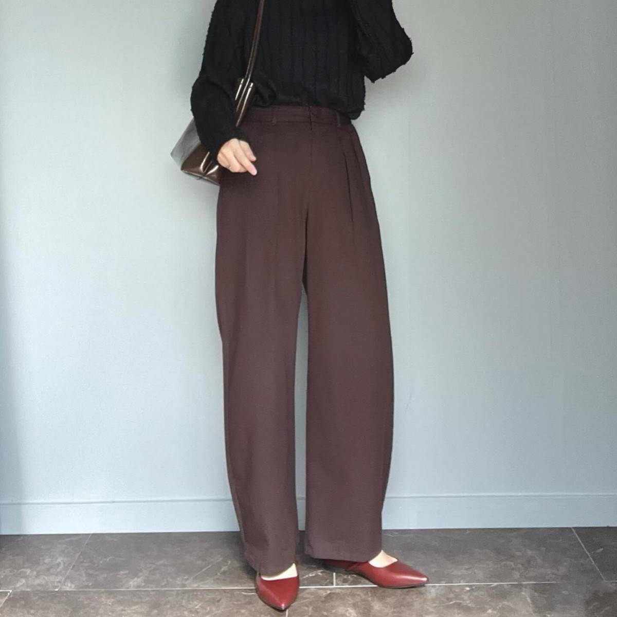 黒トップスにブラウンパンツを合わせた女性