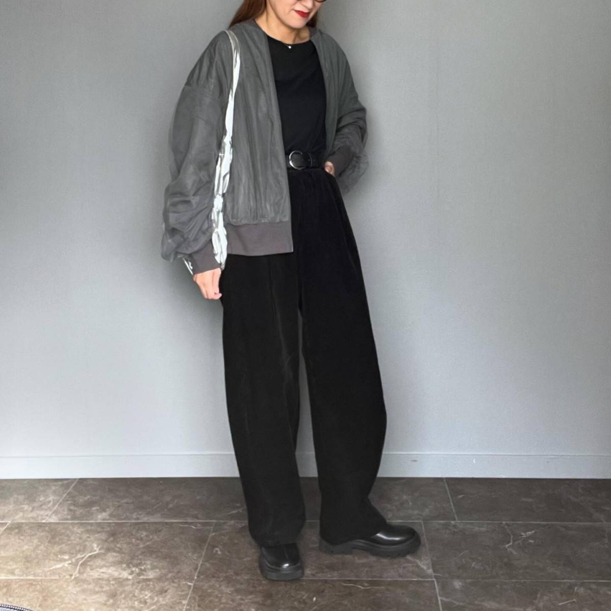 ブラックコーデにグレーのブルゾンを羽織った女性