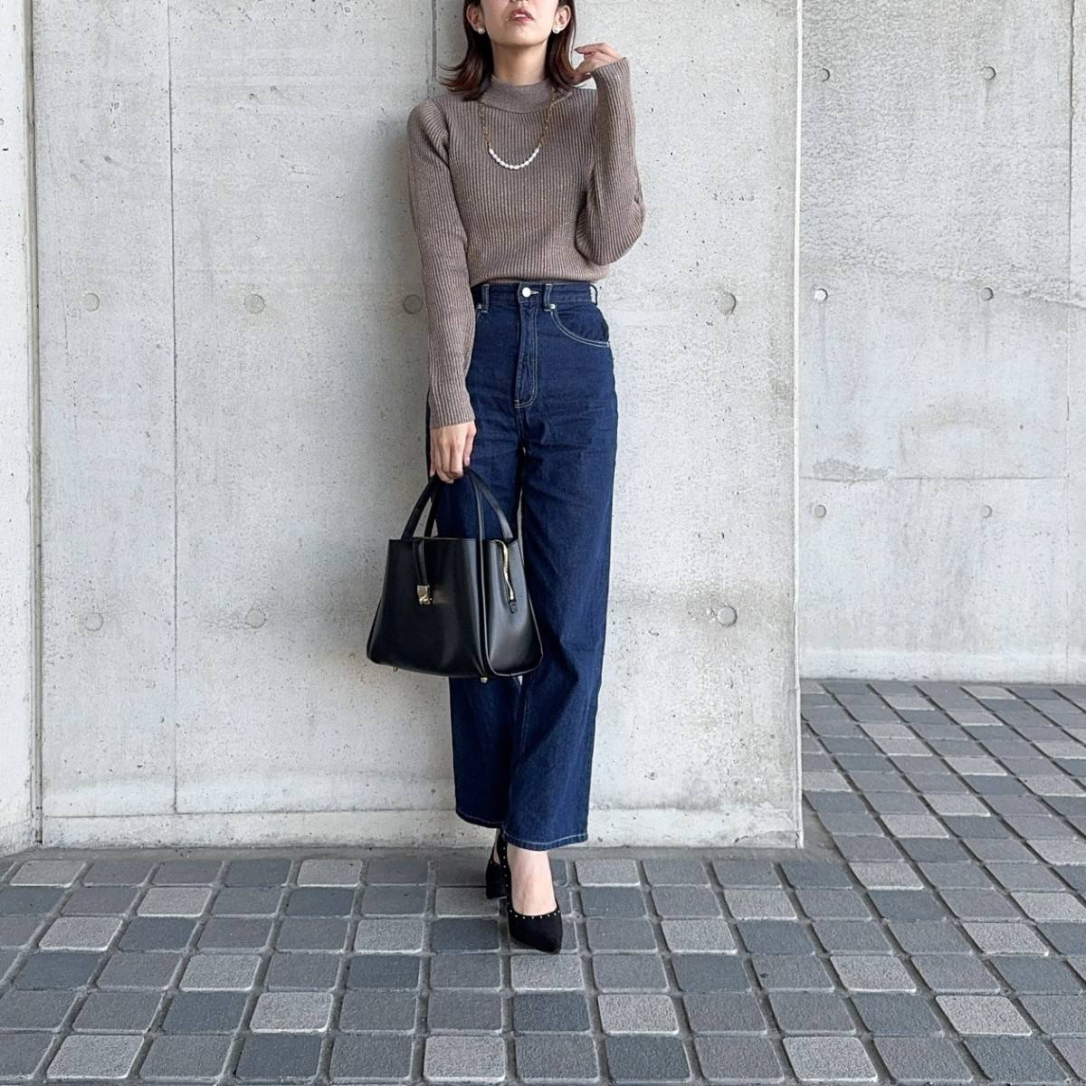 ブラウンのニットにデニムパンツを合わせた女性