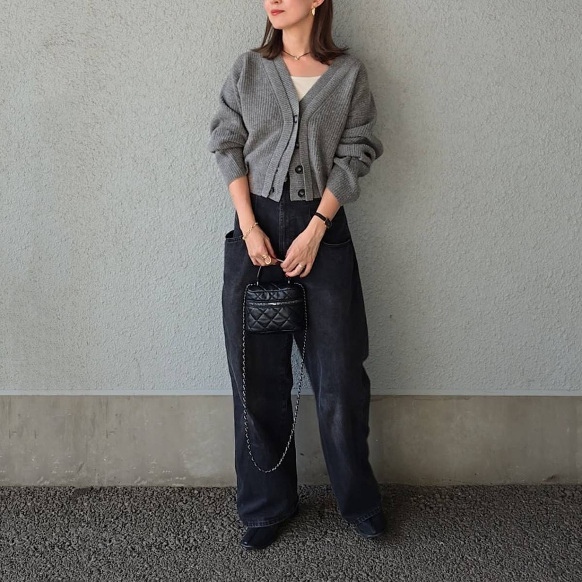 グレーのカーディガンに黒パンツを合わせた女性