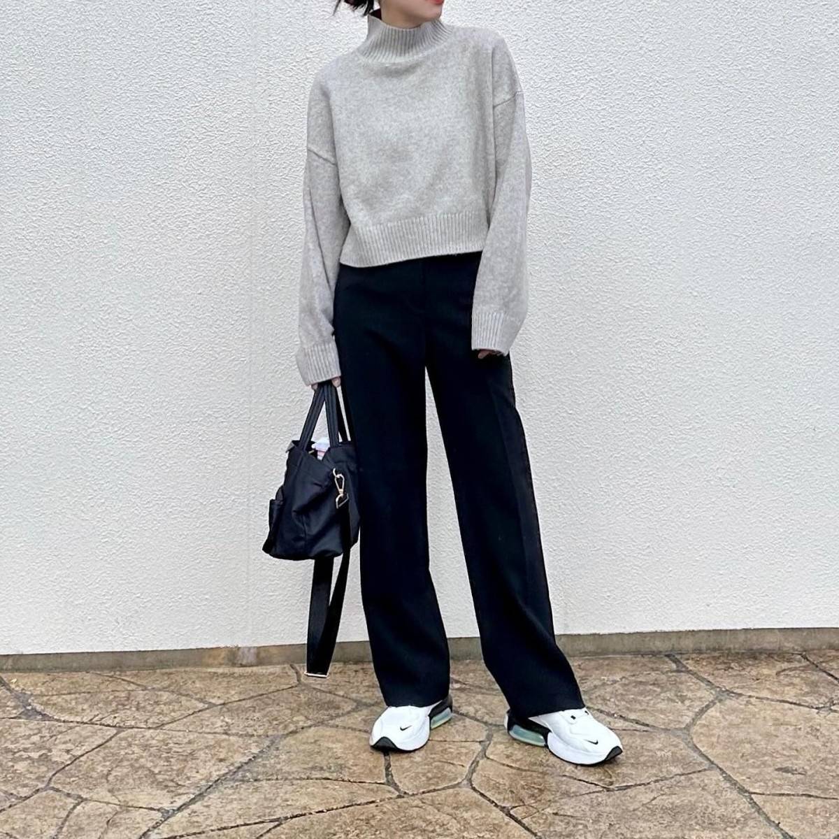 グレーのニットに黒パンツを合わせた女性
