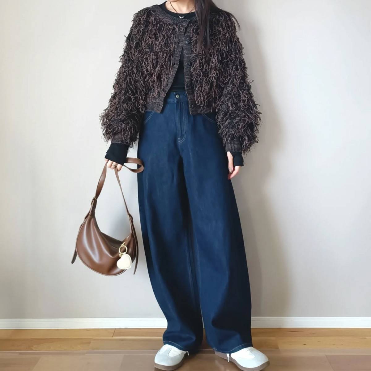 ブラウンのカーディガンにデニムパンツを合わせた女性