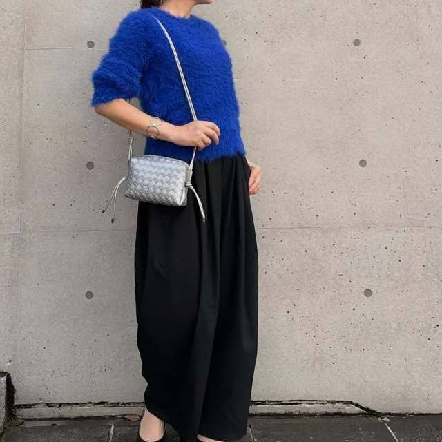 ブルーニットに黒パンツを合わせた女性