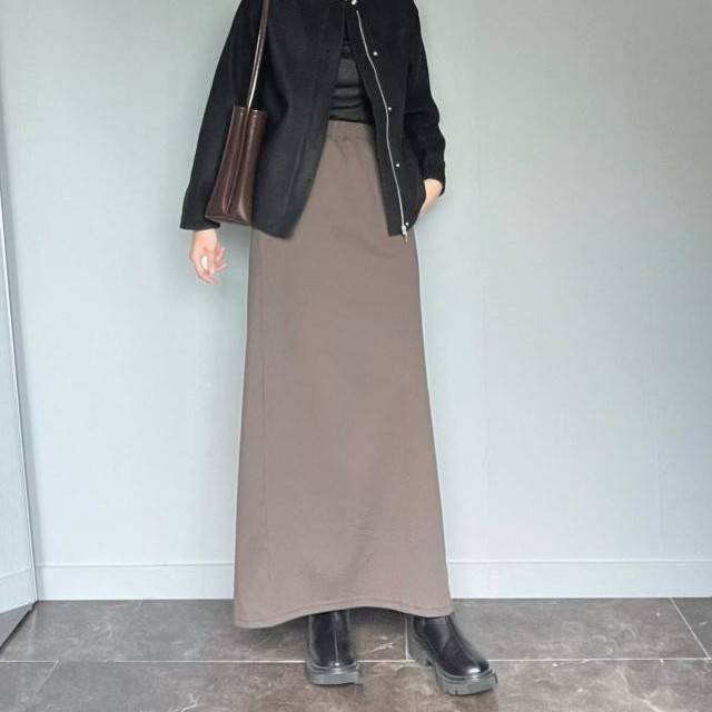 黒アウターにブラウンスカートを合わせた女性