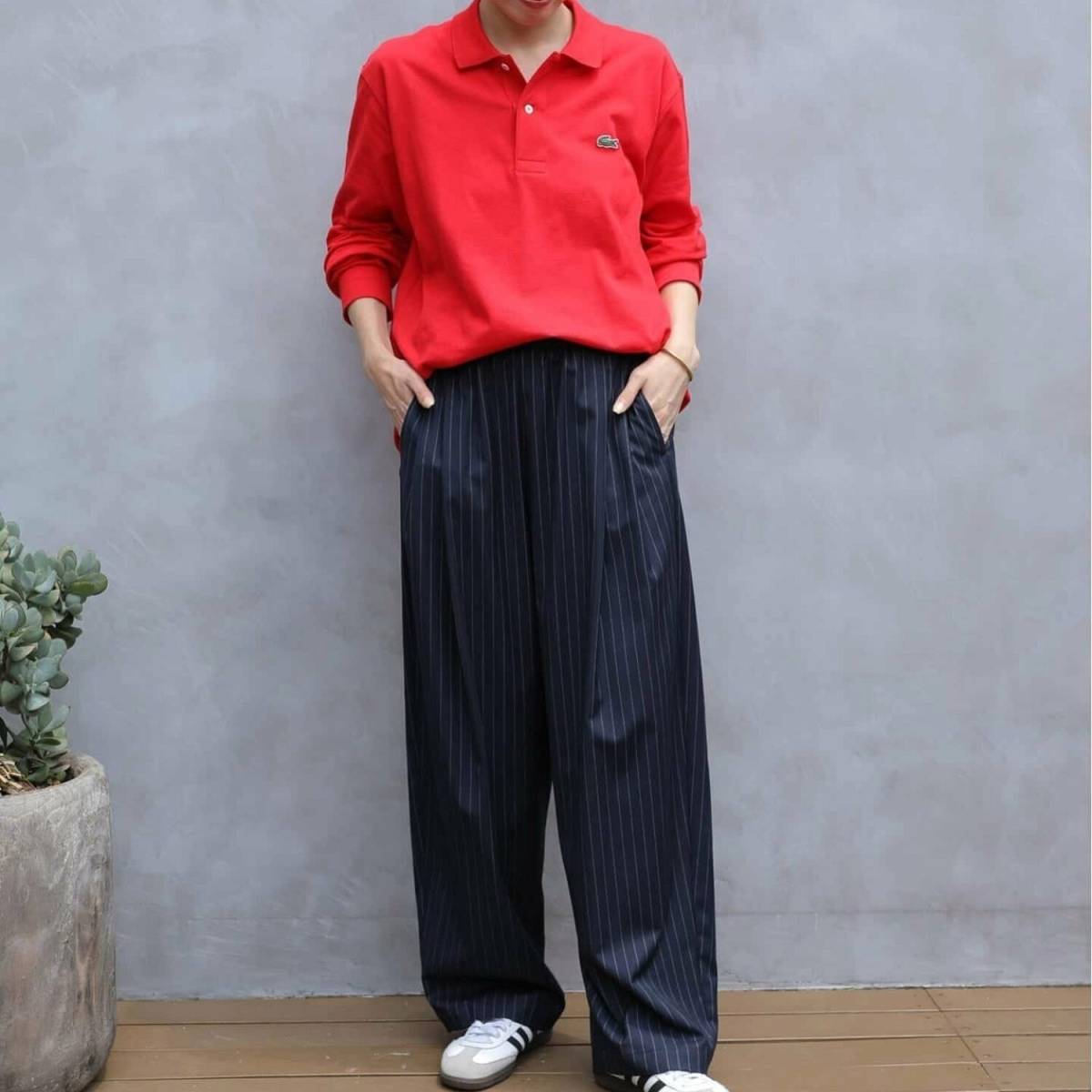 赤のポロシャツにストライプパンツを合わせた女性