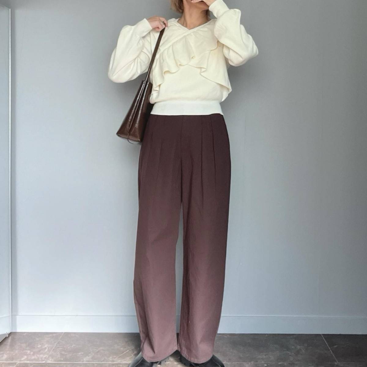 白ニットにブラウンパンツを合わせた女性