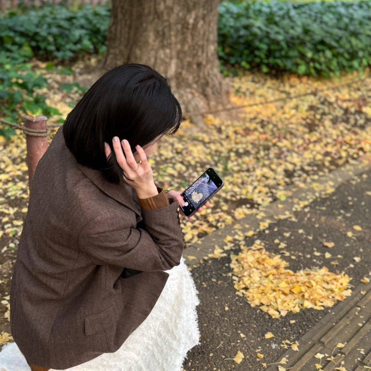 イチョウで作ったハートを撮影する女性