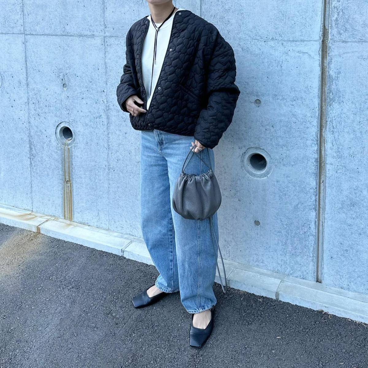 黒アウターにデニムパンツを合わせた女性