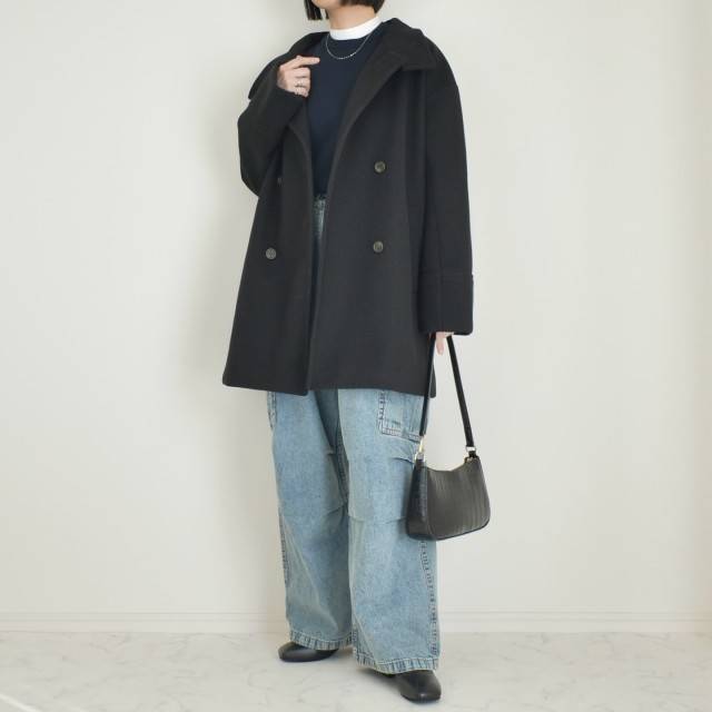 黒コートにデニムパンツを合わせた女性