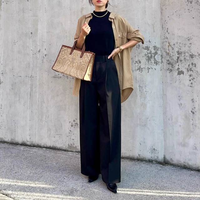 ブラックコーデの上にベージュのシャツを羽織った女性