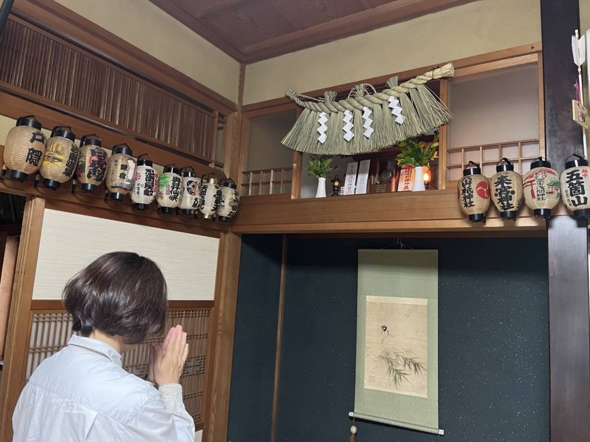 神棚に手を合わせる女性