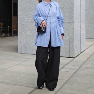  ブルーのシャツに黒パンツを合わせた女性 