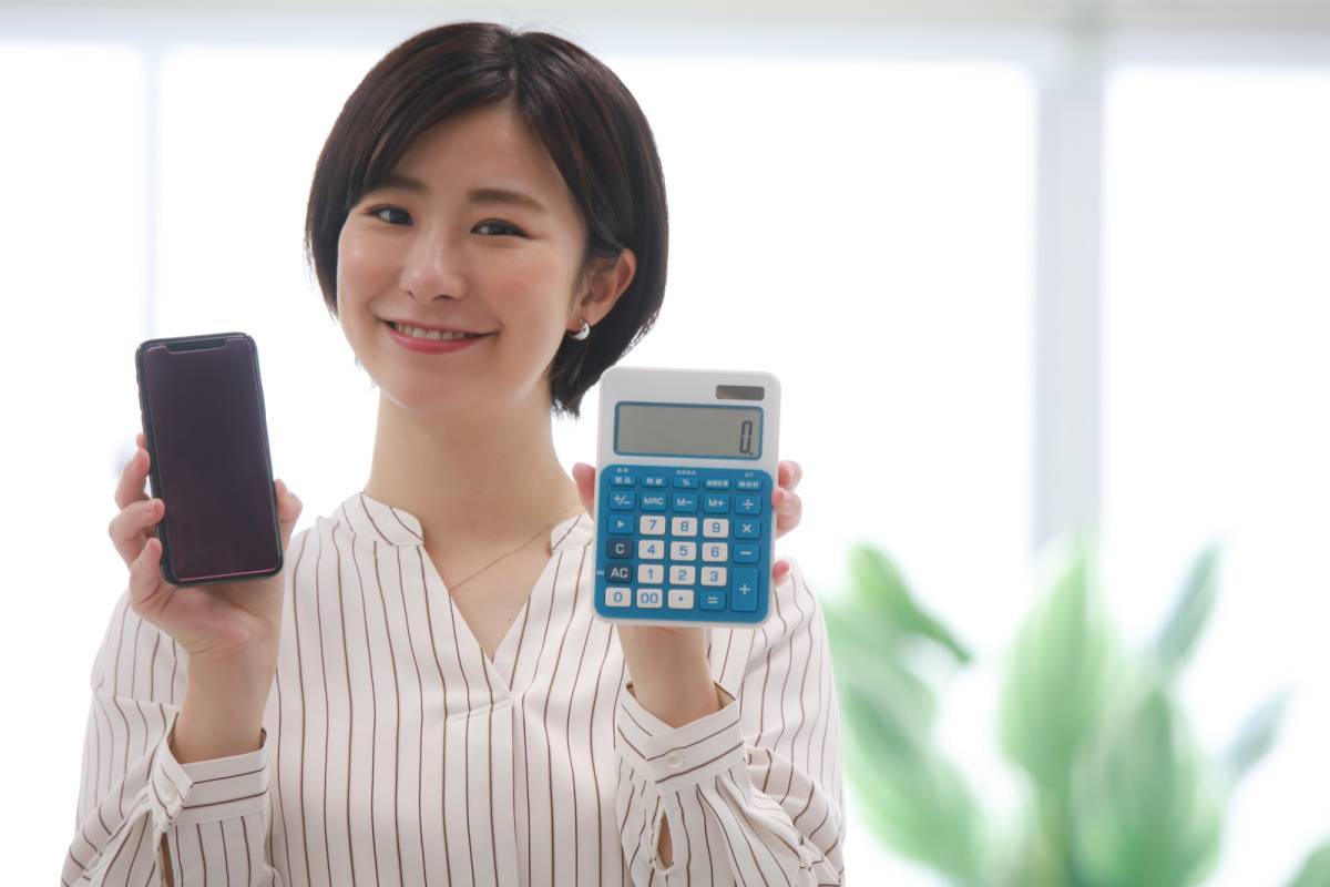 スマートフォンと電卓を持っている女性