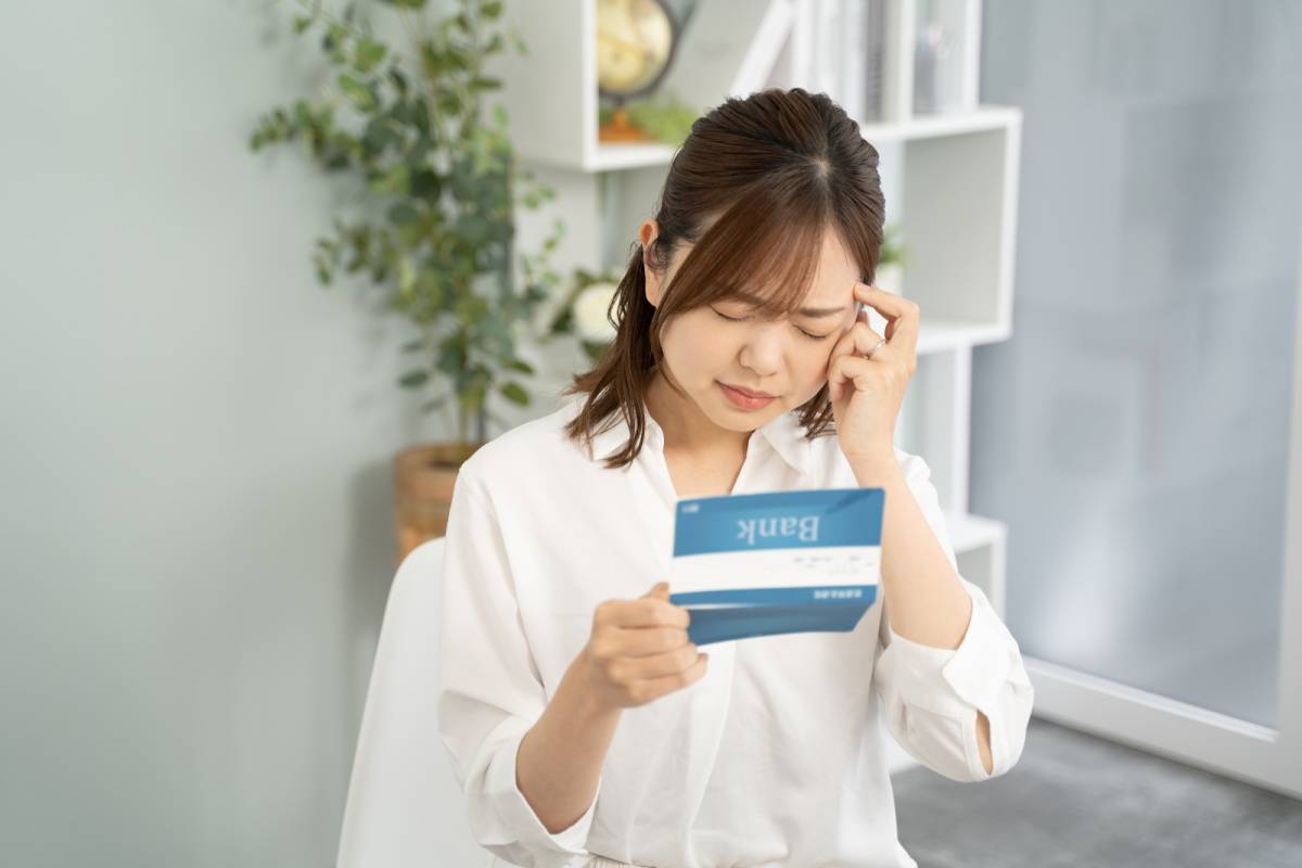 通帳を見て悩んでいる女性