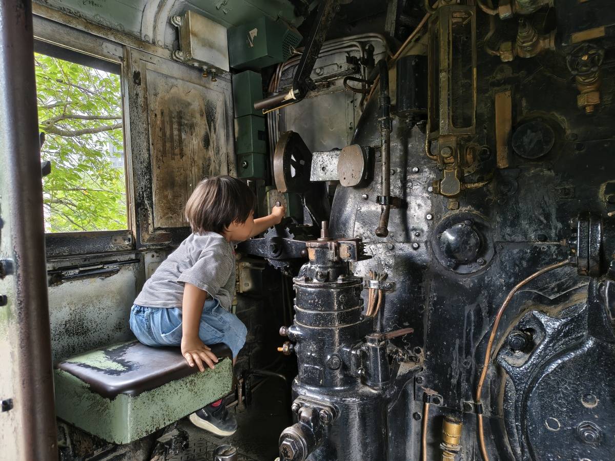 SLの機関室で運転席に座る子どもの後ろ姿