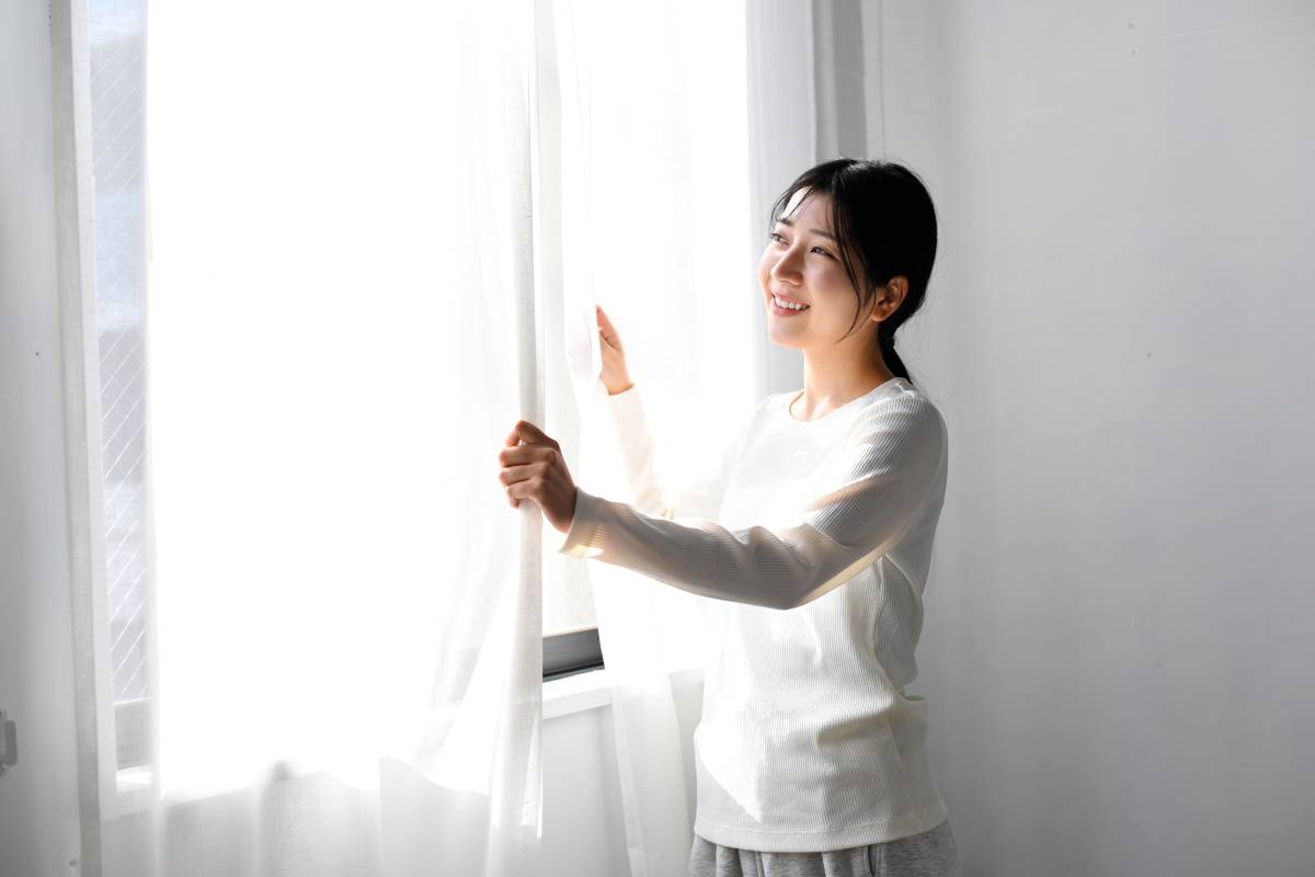 カーテンを開ける女性