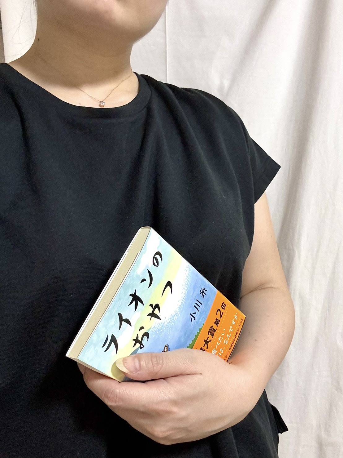小川糸著「ライオンのおやつ」を持っている女性