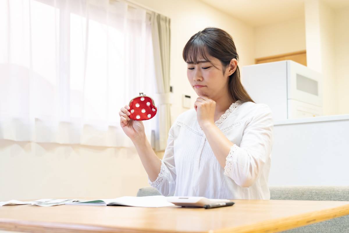 財布を持って悩んでいる女性