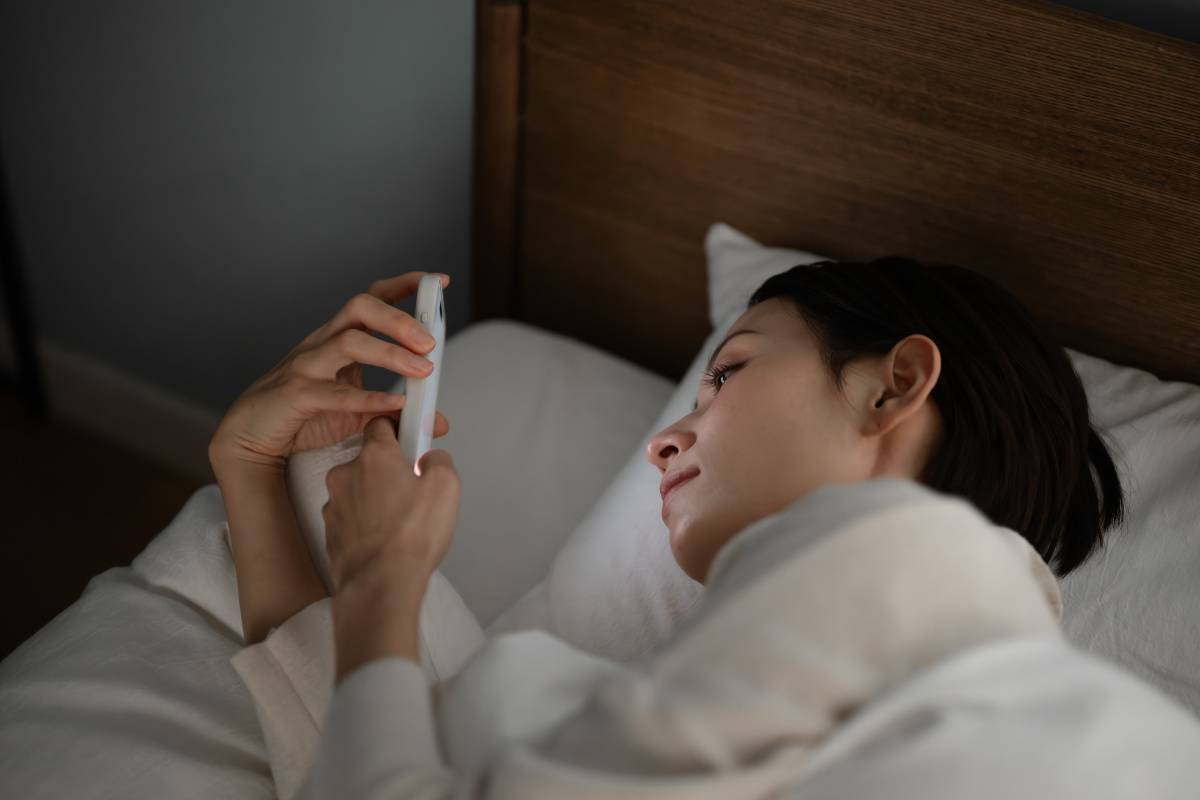 ベッドでスマホを見る女性